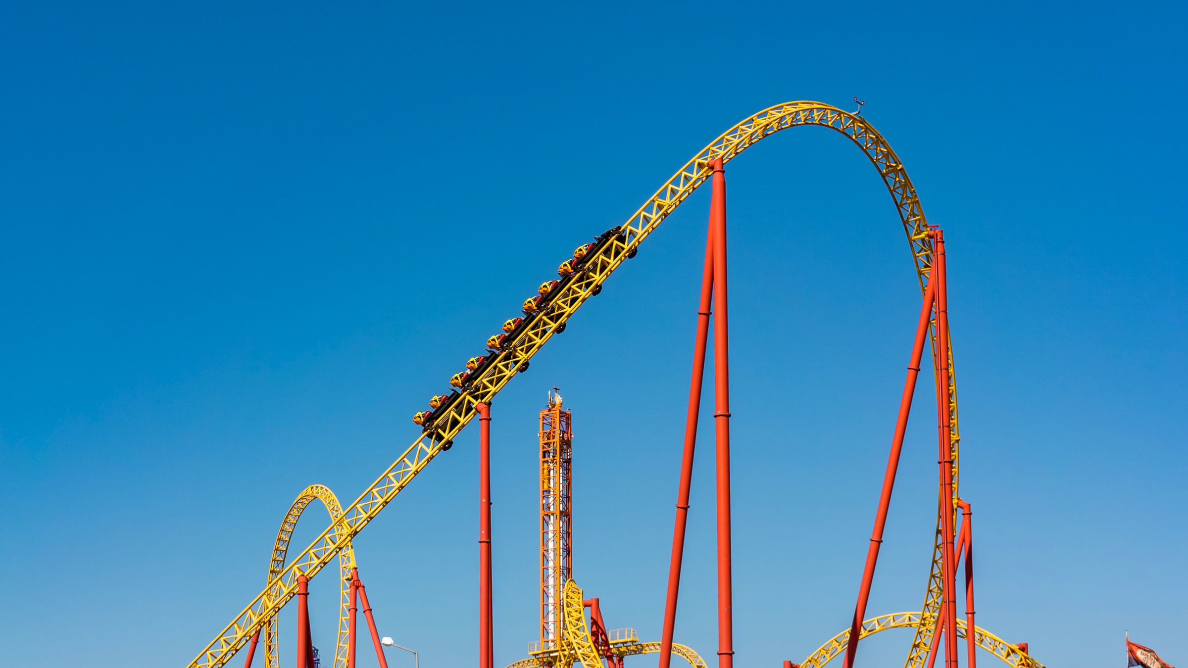 Large steel roller coaster track climbing steeply against a clear blue sky